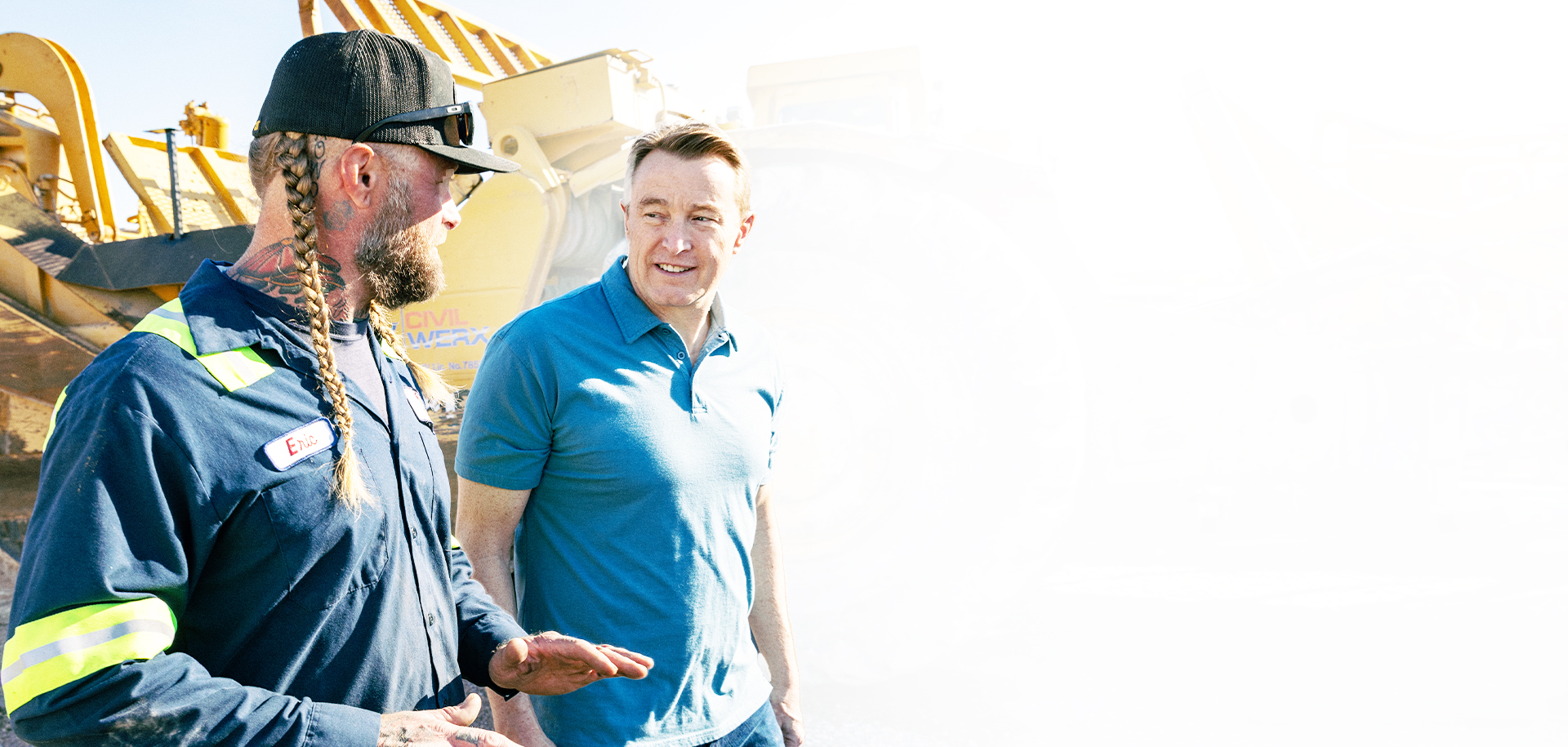 Photo of John Steinbeck in blue polo shirt talking with a worker. 